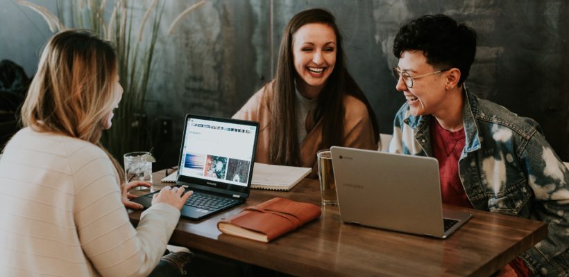 Three marketers working and laughing at their desks